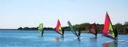 Cursos de windsurf y vela ligera en La Sotonera y campamento de inglés en Biscarrués con actividades deportivas.